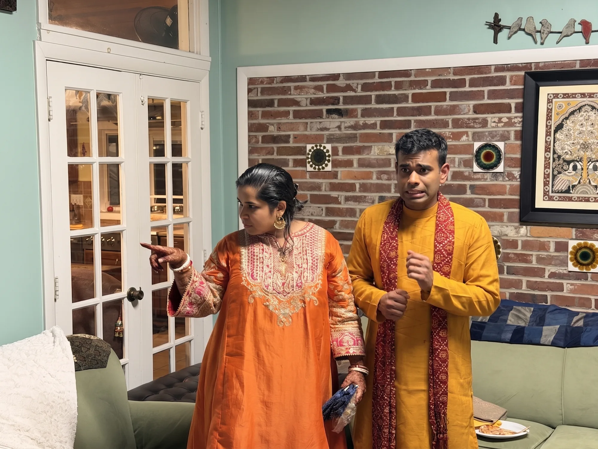 Abhijeet being pointed at in a living room, looking worried